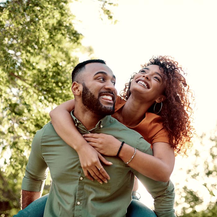 young man giving his girlfriend a piggyback ride outdoors