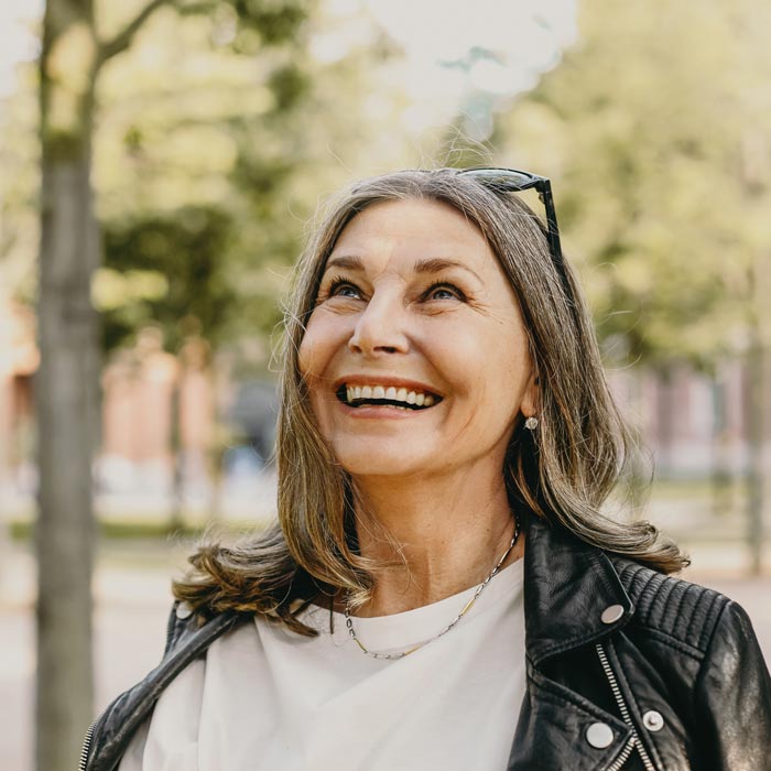 Cheerful middle aged woman wearing sunglasses on her head and black leather jacket