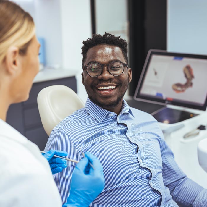Smiling man in dentist chair looking with trust at his doctor