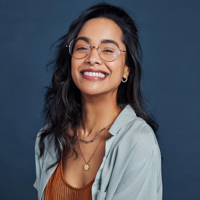 Cheerful young woman with glasses smiling and looking at camera