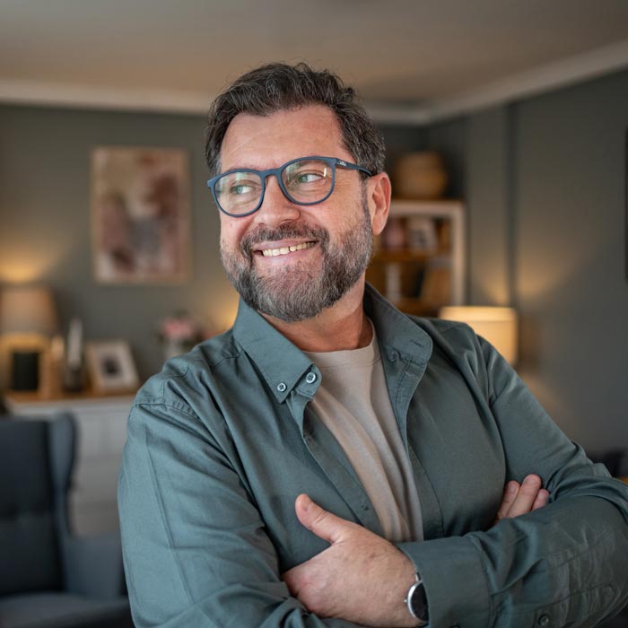 Portrait of smiling bearded man with crossed arms at home